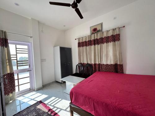a bedroom with a red bed and a window at Panwar peaceful homestay in Jhājra