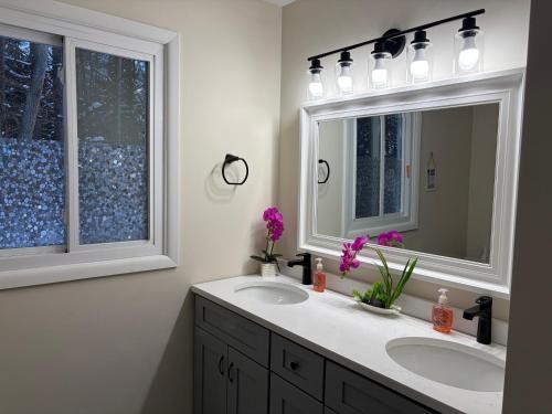 a bathroom with two sinks and a mirror and a window at Evergreen Escapes 4 BR with Game Room, Firepit near Kalahari and Camelback in Long Pond