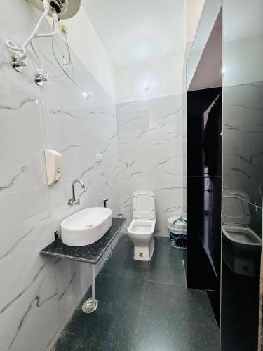 a white bathroom with a sink and a toilet at Panwar peaceful homestay in Jhājra