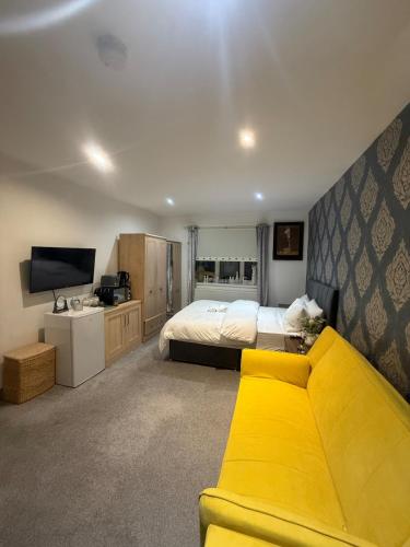 a bedroom with a bed and a yellow couch at Eastern Bridge House in Spinney Hill