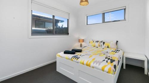 a white bedroom with a bed and a window at Beach Serenity in Sunderland Bay