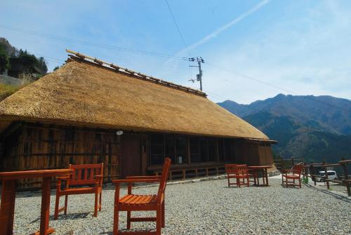 a hut with chairs and tables and a thatch roof at Tougenkyo Iya no Yamazato in Miyoshi