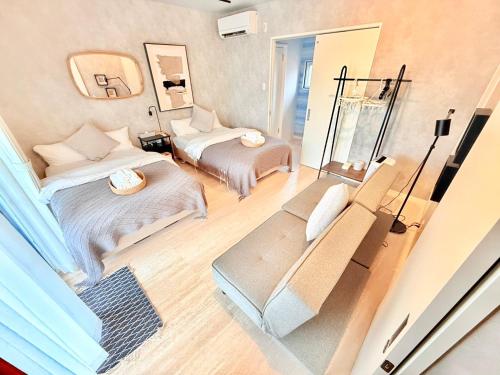 a small room with two beds and a couch at Plus Life Shiraho A号室 in Ishigaki Island
