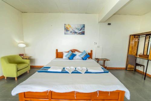 a bedroom with a large bed and a green chair at Leesuma Homestay in Ban San Pu Loei