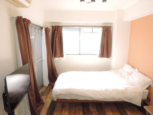 a bedroom with a bed and a window at フレクション大工町 in Miyazaki