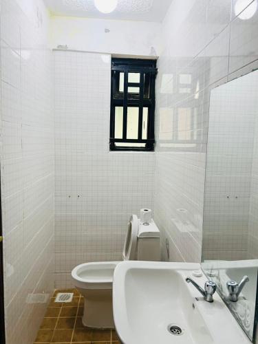 a white bathroom with a sink and a toilet at Legoland Residence in Migori
