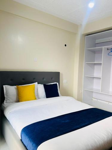a bedroom with a bed with yellow and blue pillows at Legoland Residence in Migori