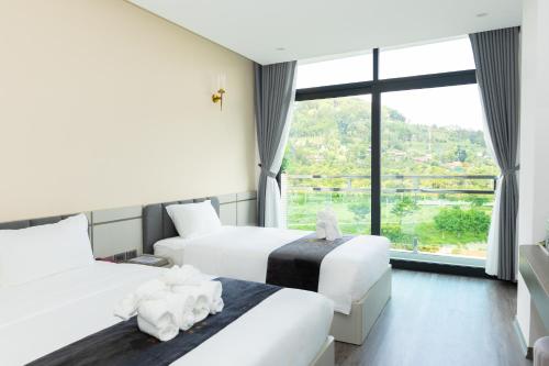 a hotel room with two beds and a large window at NaCo Hotel in Lao Cai