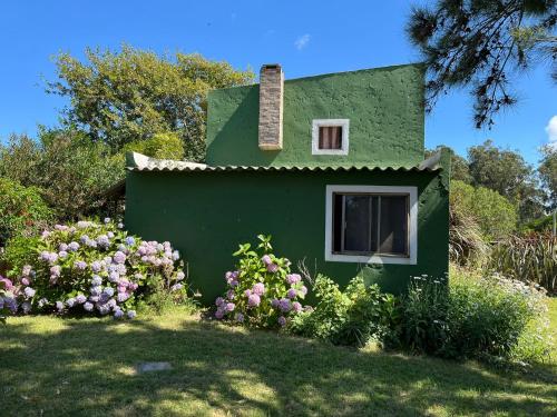 a small green house with a window and flowers at Carranca TH5 in Costa Azul