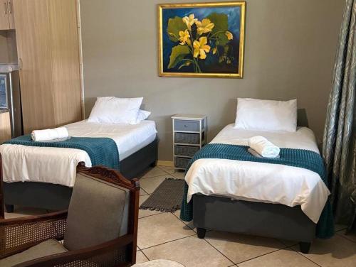 a room with two beds and a painting on the wall at Hekpoort Rorymi Guest farm in Hekpoort