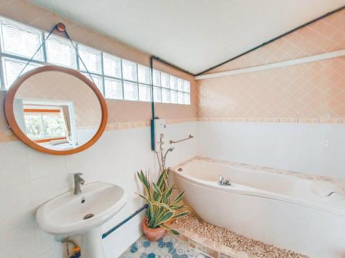 a bathroom with a sink and a tub and a mirror at Bangsaphan Resort in Bang Saphan