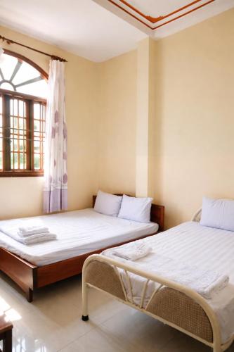 two beds in a room with a window at Thanh Tâm Hotel in Can Tho