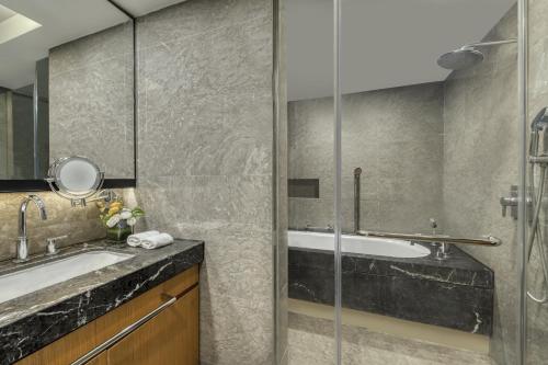 a bathroom with a shower and a tub and a sink at Ascott IFC Guangzhou in Guangzhou
