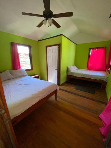a green bedroom with two beds and a ceiling fan at 4J's Cabins in Santa Familia
