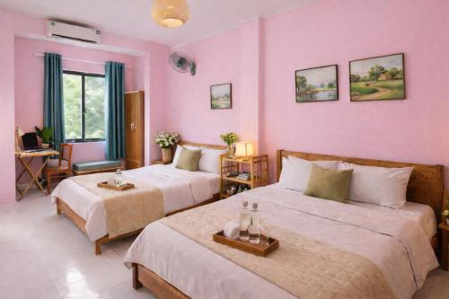 two beds in a room with pink walls at HangNga homestay - hotel in Phủ Từ Sơn