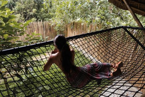 a woman in a dress laying on a net at Bamboo Jungle Villa's in El Nido