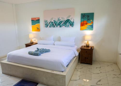 a bedroom with a bed with white sheets and paintings at Swell Hotel, Pool Bar & Restaurant in Tanah Lot