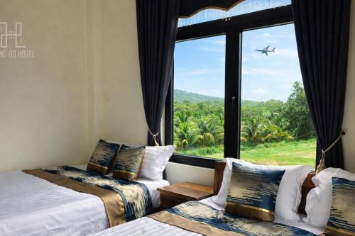 a room with two beds and a window with an airplane at Hoàng Đô Hotel in Phú Quốc