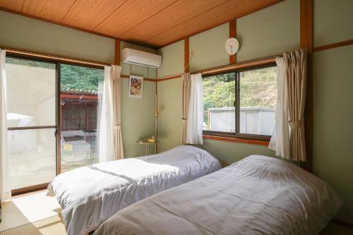 two beds in a room with a window at くつろ郷Kutsuro-go in Kawatana
