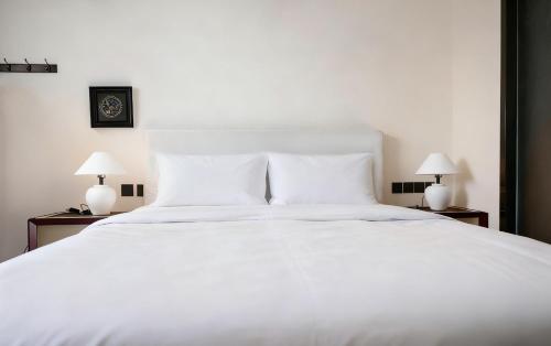 a white bed with two lamps on two tables at Wave Nest 汐宿 in Chongqing