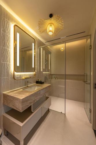 a bathroom with a sink and a shower and a mirror at Emerald Boutique Hotel Phú Quốc in Phú Quốc