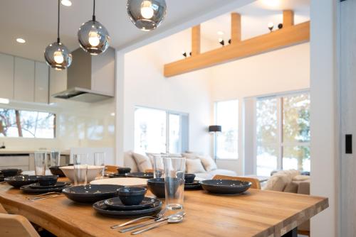 a dining room with a wooden table with plates and glasses at Grouse Lodge -5 mins to ski field by walk- in Furano