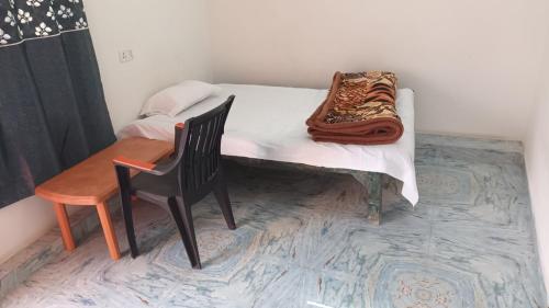 a small bed with a chair and a blanket on it at Sujata Buddha Homestay in Bodh Gaya