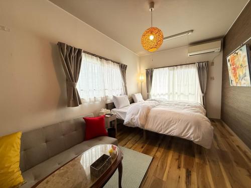 ein Schlafzimmer mit einem Bett, einer Couch und einem Tisch in der Unterkunft 宿Luce in Okayama