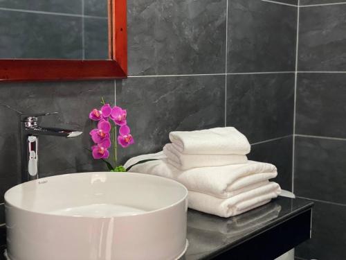 a bathroom sink with towels and a flower on a counter at HomeStore Apartment in Siem Reap