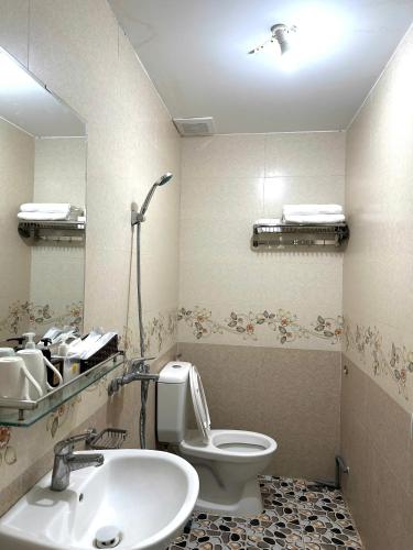 a bathroom with a toilet and a sink and a mirror at Oriio Hotel Cát Bà in Cat Ba