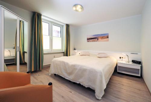 a bedroom with a white bed and a chair at Fietje 206 - Hohen Wieschendorf in Hohen Wieschendorf