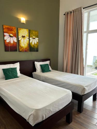 Twee bedden in een kamer met schilderijen aan de muur. bij The Suite 262 in Negombo