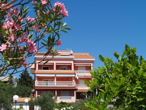 a pink building with trees in front of it at Apartments Banic in Rab