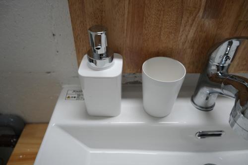a white sink with two cups on top of it at Retreat Ginoza in Ginoza