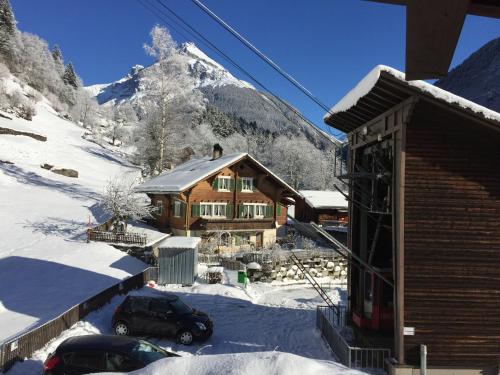 a log cabin in the snow with a mountain at Gästehaus Schäfli in Intschi