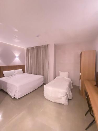 a hotel room with two beds and a desk at Hotel Abba Goiana PE in Goiana