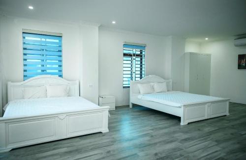 two white beds in a white room with two windows at Nice's Hotel Ninh Binh in Ða Gia