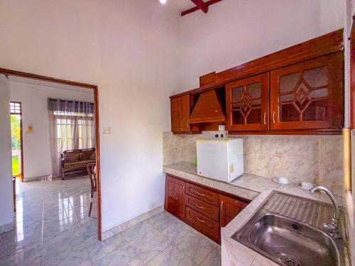 a kitchen with wooden cabinets and a sink at Airport Green View Hotel Katunayake in Andiambalama