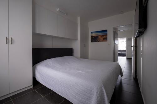 a bedroom with a white bed and white cabinets at Appartement Ann in Blankenberge