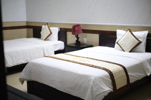 two beds in a hotel room with white sheets at Bảo Cường Hotel in Hương Hóa