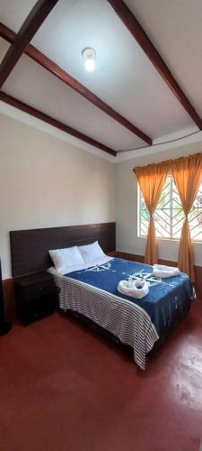 a bedroom with a bed with blue sheets and two windows at Mítica, Casa Hospedaje in Sauce