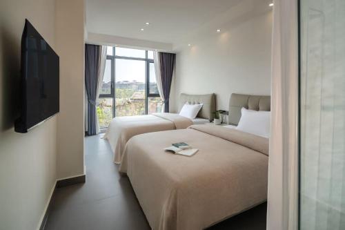 two beds in a hotel room with a television at 样样好民宿 in Jinghong
