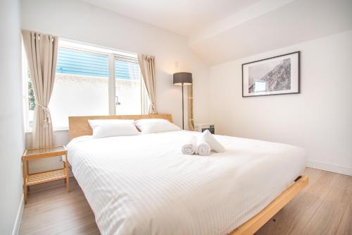 a bedroom with a large white bed with a window at Grouse Lodge -5 mins to ski field by walk- in Furano