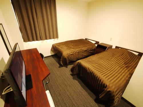 a hotel room with two beds and a flat screen tv at Business Hotel Fiz Nagoya Airport in Toyoyama