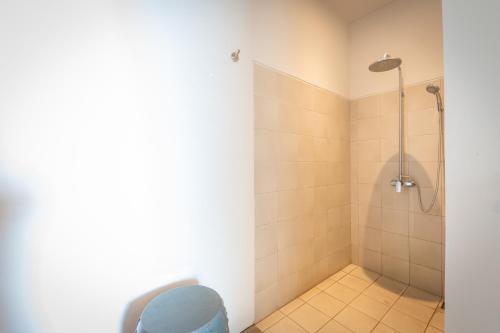 a bathroom with a shower with a blue trash can at Lusa Beach Studios Lovina in Lovina