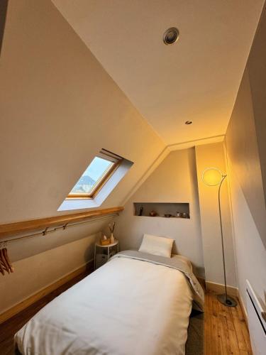 a attic bedroom with a bed and a window at Charmante maison moderne et cosy in Aunay-sur-Odon