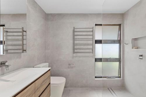 a bathroom with a toilet and a glass shower at Sunsets on Kalang in Urunga