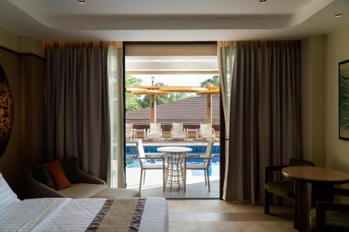 a hotel room with a bed and a patio with a table at Coron Westown Resort Premier in Sampong
