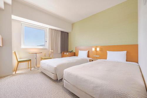 a hotel room with two beds and a window at Candeo Hotels Fukuyama in Fukuyama