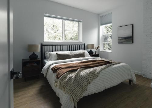 a bedroom with a large bed and two windows at Lokis Loft and Cellar at the 1896 Building in Kaslo